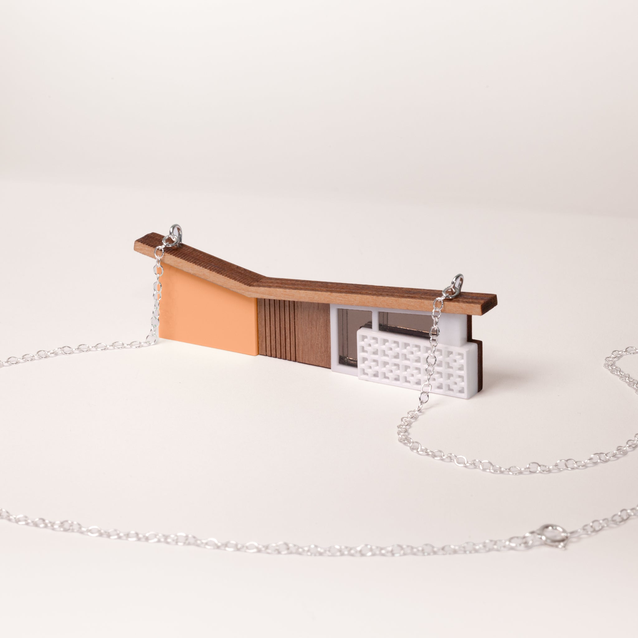 orange butterfly roof house necklace with silver chain on a white background