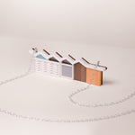 Small model of a modernist house mader from acrylic and wood with silver chain on a beige background