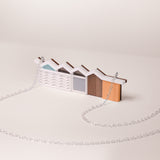 Small model of a modernist house mader from acrylic and wood with silver chain on a beige background