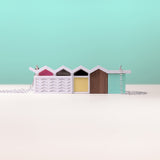 Colourful palm springs inspired miniature house necklace with a white base on a light blue background
