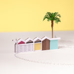 Close up of a palm springs house necklace with silver chain and palm tree on a yellow background