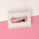Pink miniature house pendant with a midcentury modern shape in a white gift box on a pink background