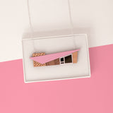 Pink miniature house pendant with a midcentury modern shape in a white gift box on a pink background