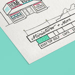 A close-up of a white textured paper art print featuring a hand-drawn black ink illustrations of midcentury roadside buildings such as a 'HOME VIDEO' store, mini golf and cafe. Set against an aqua background.