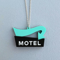 A black and mint pendant in the shape of a miniature motel sign, hanging against a plain background on sterling silver chain.